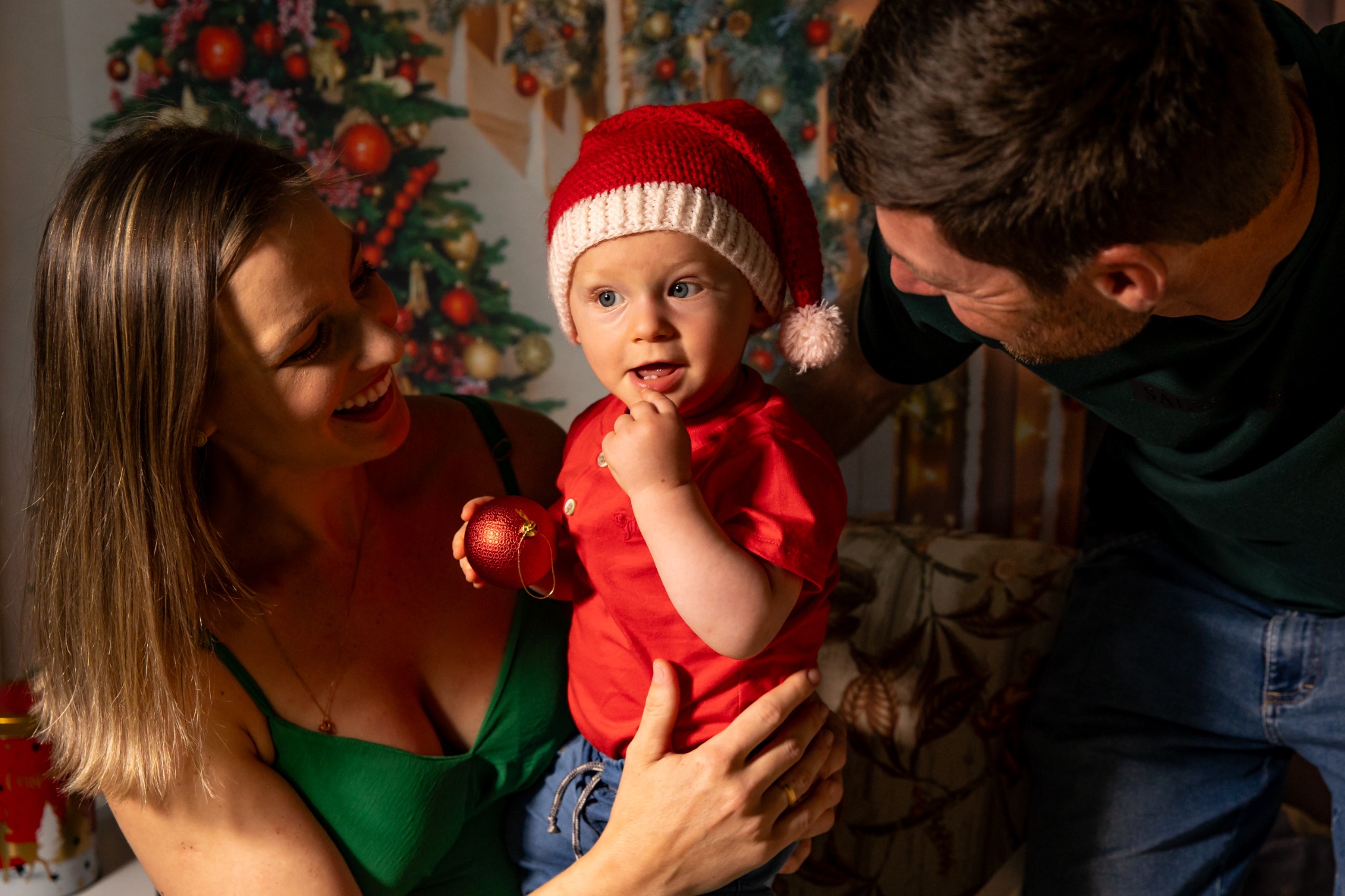 Pais sorrindo para o filho durante um ensaio de Natal